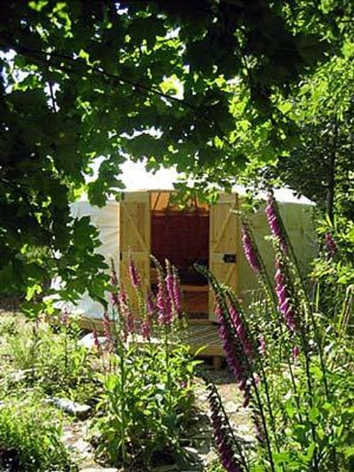 Trallwyn Yurt for camping in style with wood floor, rugs and woodstove, it sleeps 2-4 on futons and